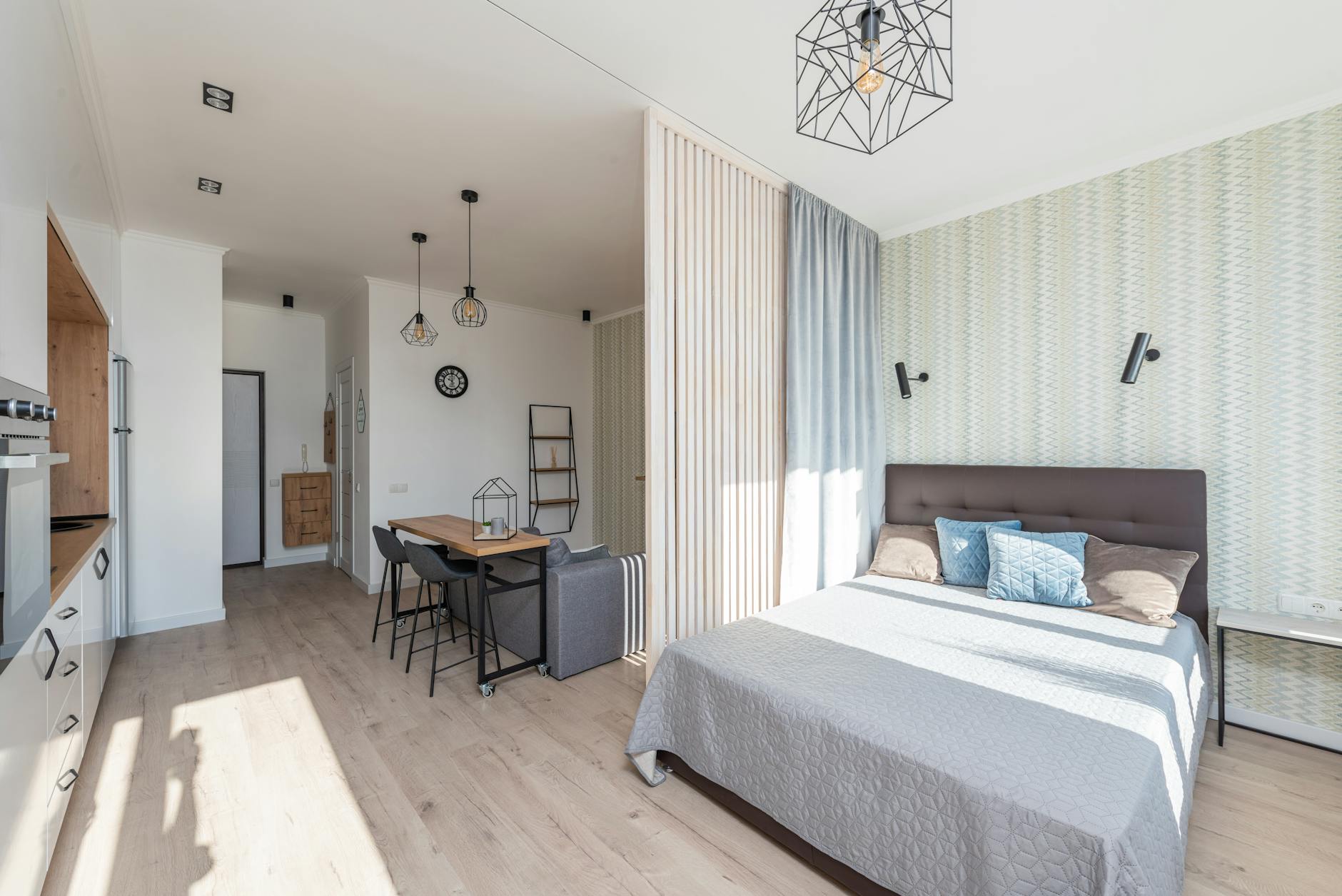 Jasna kawalerka do wynajęcia na Airbnb z łóżkiem, sofą i białą kuchnią