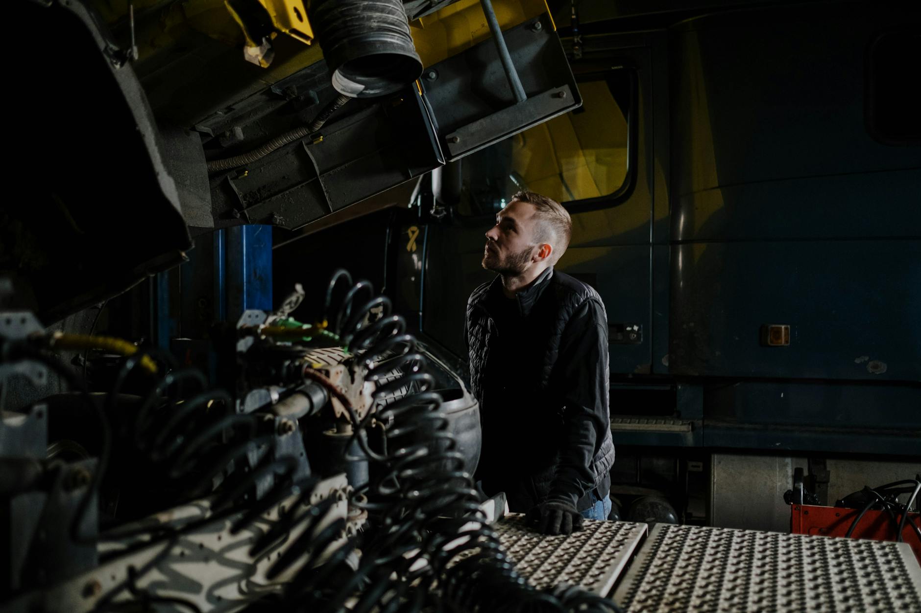 Mechanik ciężarówek sprawdza silnik w warsztacie Mechanik ciężarówek sprawdza silnik w warsztacie