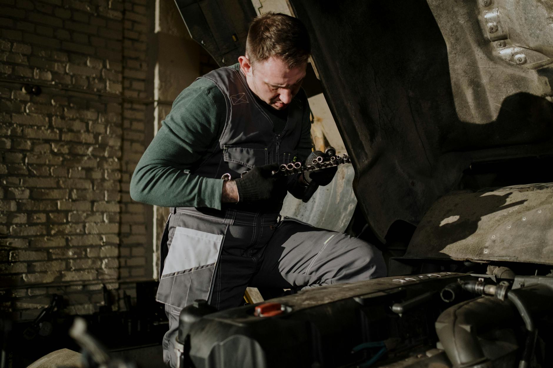 Mechanik w kombinezonie ogląda części silnika ciężarówki w warsztacie